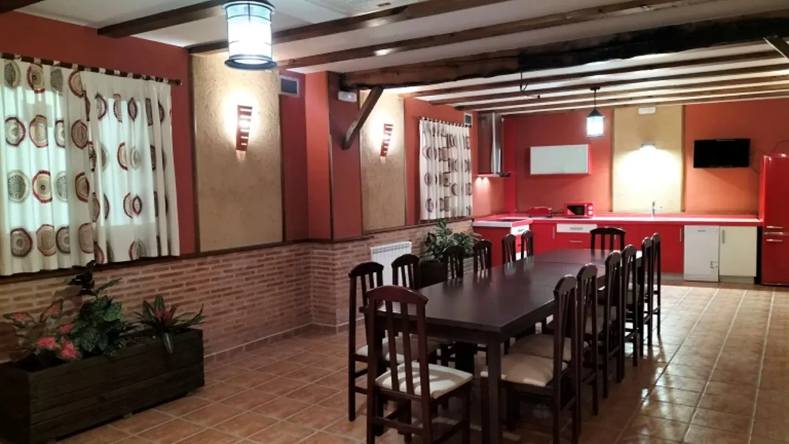 Salón comedor con mesa larga de madera y cocina al fondo