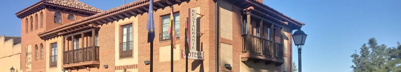 Fachada de ladrillo del Hotel Rural Venta del Alón, con balcones de madera y el cartel de restaurante